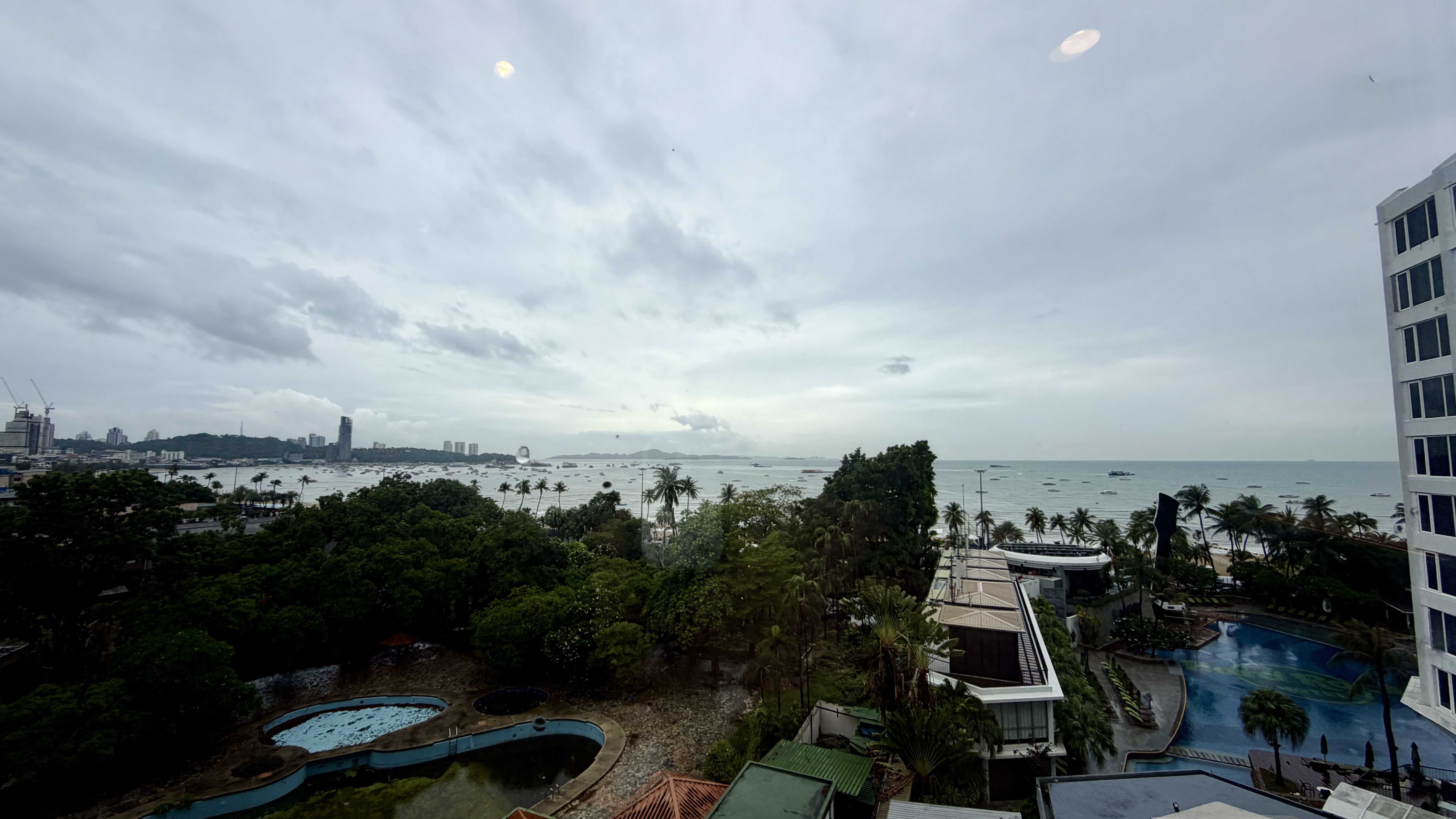Pattaya beach can be seen from a hotel window. The day is overcast